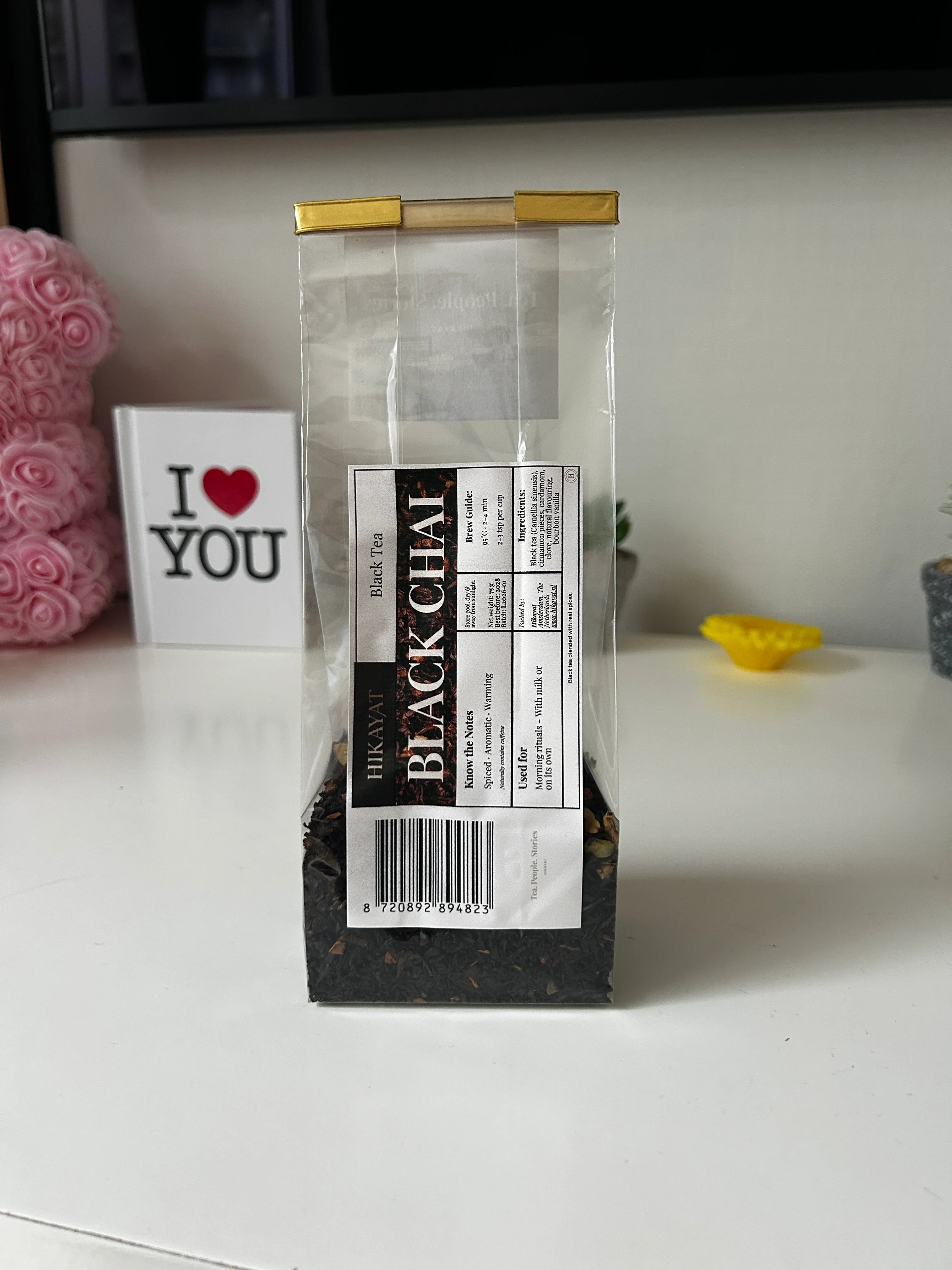 Black Chai tea blend in clear packaging with gold seal, showcasing organic spices and tea leaves