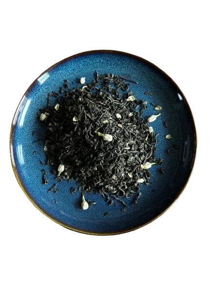 Organic black tea leaves with jasmine buds on a blue ceramic plate