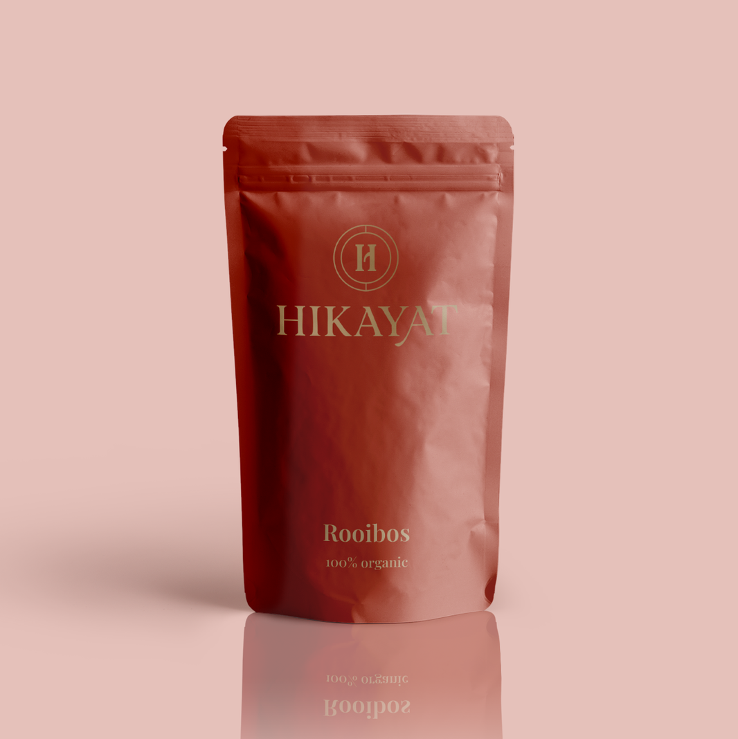 Red Hikayat Rooibos packaging on a pink background